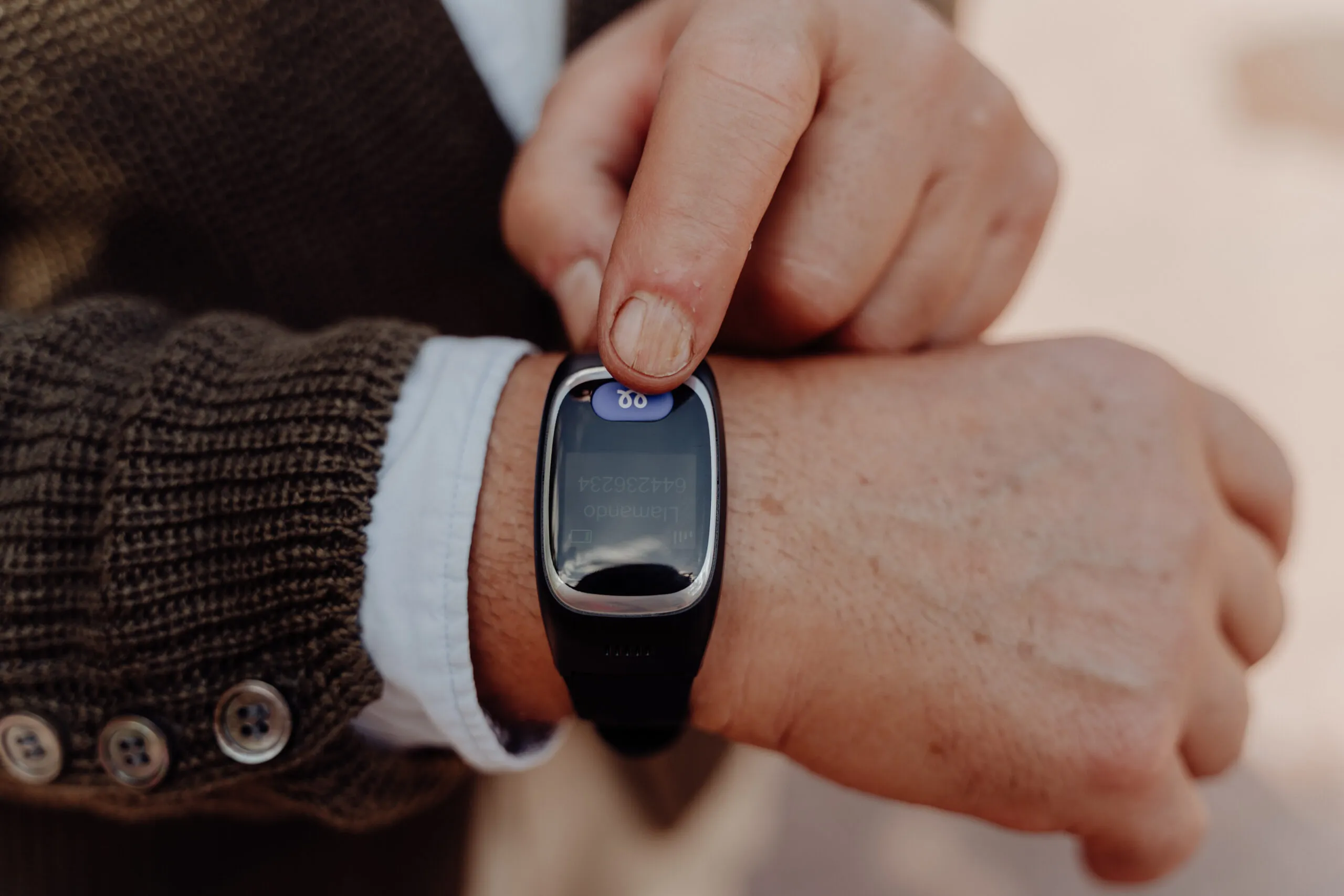 Señor mayor presionando el botón del reloj Durcal de teleasistencia
