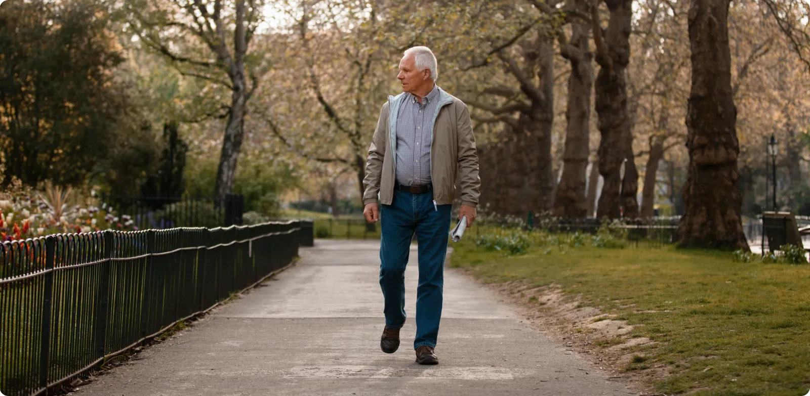 Vista frontal de un adulto mayor caminando por un sendero arbolado con expresión de búsqueda y mirada desorientada. Ilustra la importancia de la teleasistencia de Durcal para mantener la autonomía de quienes viven solos.