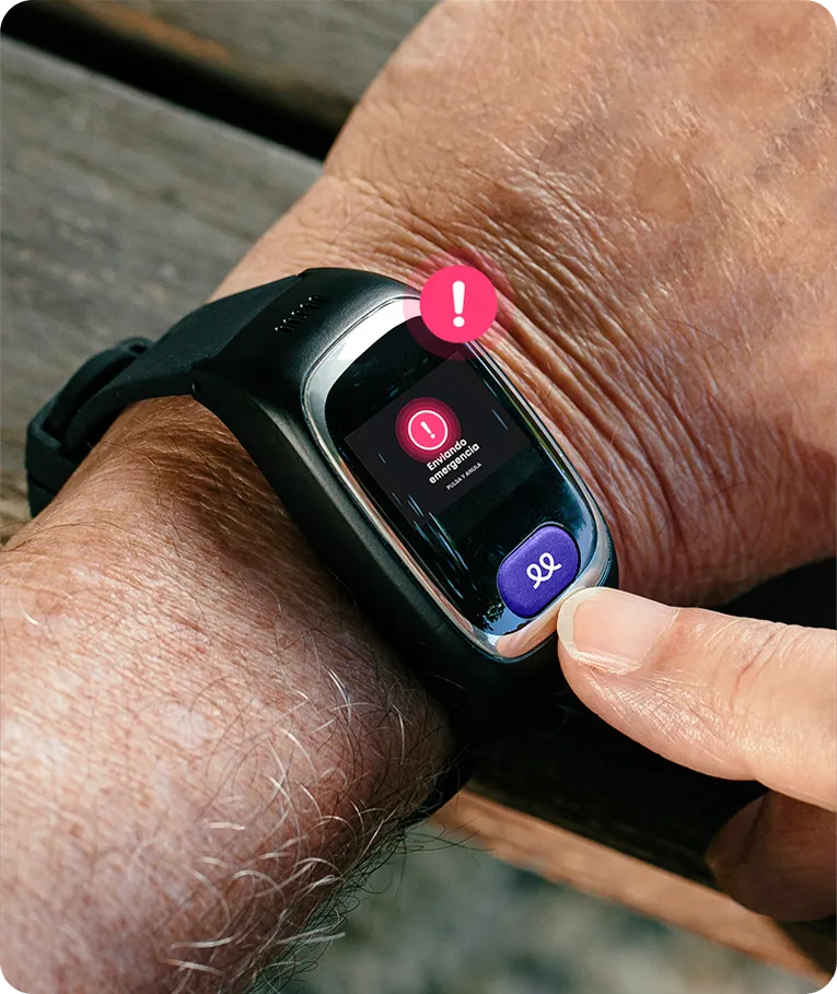 Primer plano del reloj inteligente de teleasistencia Durcal en la muñeca de una persona. La pantalla muestra un aviso de alerta roja y un botón morado de SOS, con un icono de exclamación rosa flotando sobre el dispositivo.