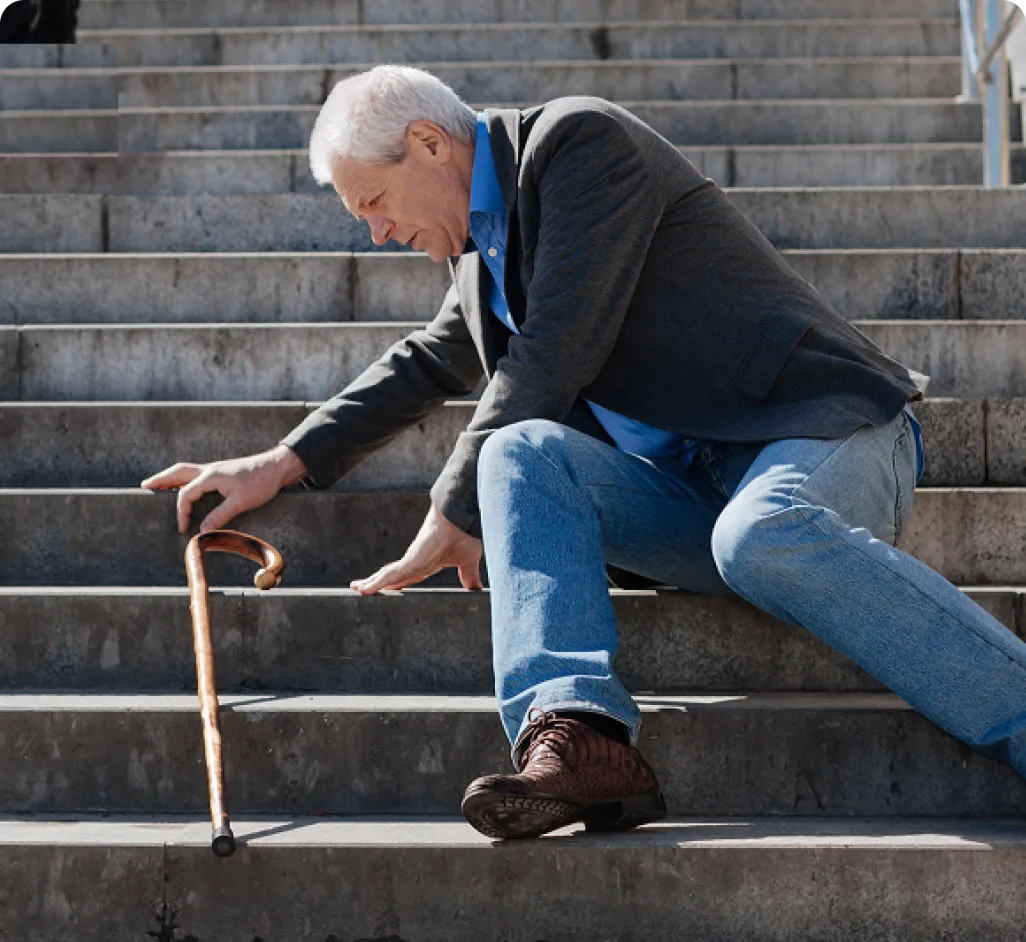 Hombre mayor caído en unas escaleras de ciudad. La imagen resalta el riesgo de accidentes domésticos y exteriores para la tercera edad, subrayando la utilidad de llevar un reloj inteligente con GPS y sensor de caídas para solicitar ayuda inmediata.