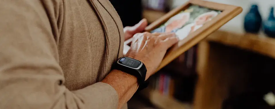 Persona mayor con reloj Durcal en la muñeca, sosteniendo un marco con una foto familiar en un ambiente hogareño
