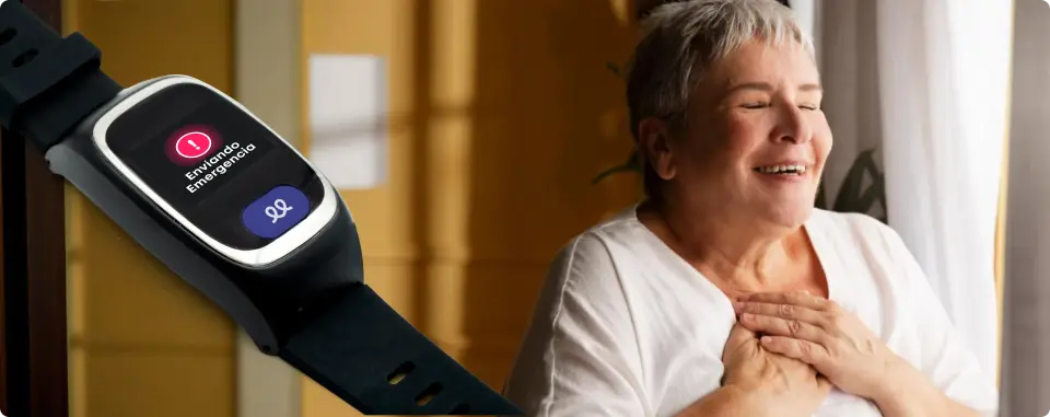 Una mujer mayor tirada en el suelo sobre una alfombra estampada es asistida por dos personas. La mujer lleva un smartwatch negro con un icono de exclamación rojo parpadeante en la pantalla.