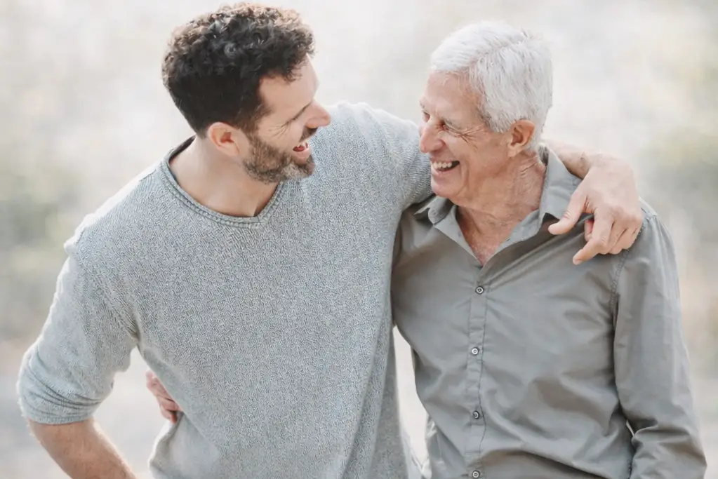 Padre e hijo sonriendo juntos con el reloj de teleasistencia Durcal al fondo