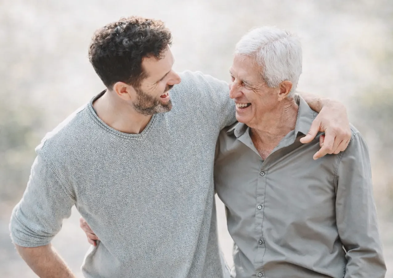 Padre e hijo sonriendo juntos con el reloj de teleasistencia Durcal al fondo