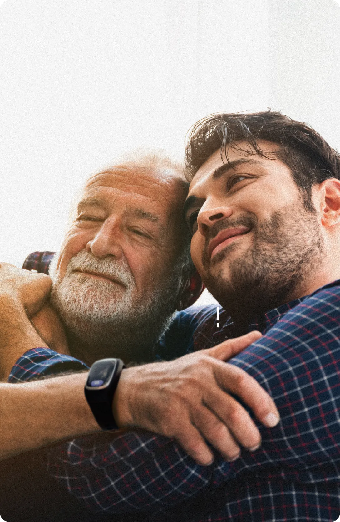 Elderly man and younger man hugging and smiling