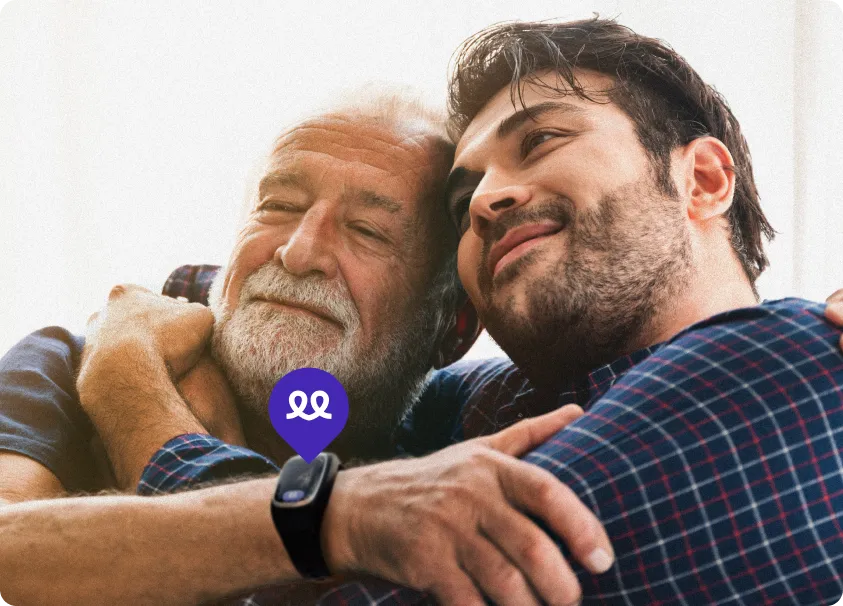 Elderly man and younger man hugging and smiling