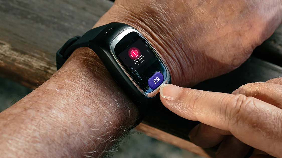 Smartwatch on elderly person's wrist showing a red alert icon on screen